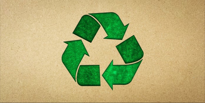 Green recycling symbol on brown paper. Concepts of reducing waste and reusing, symbolism of environmentally friendly products, CSR, zero waste. photo