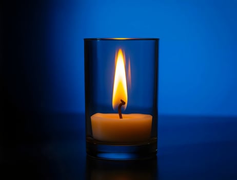 A lit candle in a glass on a dark table photo