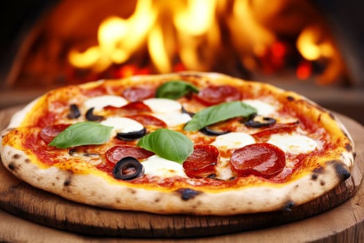 A pizza is shown on a wooden board with a fire in the background photo