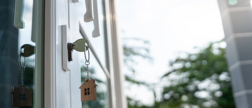 Landlord key for unlocking house is plugged into the door. Second hand house for rent and sale. keychain is blowing in the wind. mortgage for new home, buy, sell, renovate, investment, owner, . photo