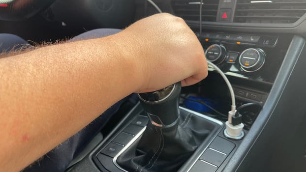 A person's hand is holding a car's shift knob photo
