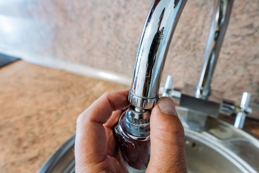 An individual is diligently fixing a leaking kitchen sink faucet to ensure it operates properly and efficiently, while also aiming to prevent unnecessary water waste that can occur photo