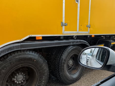 A closeup of a bright yellow truck showcases its robust tires and shiny side mirror, highlighting the vehicles industrial strength and versatile capabilities in various applications photo