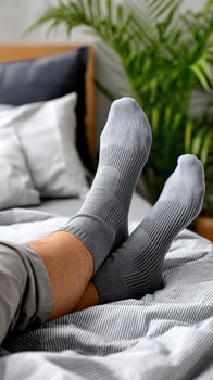 A person wearing gray socks on a bed photo