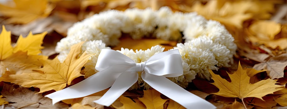 A wreath of white flowers and leaves with a white ribbon photo