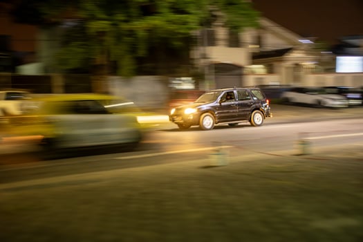 Urban scene at night in Abidjan, SUV moving on a busy avenue photo