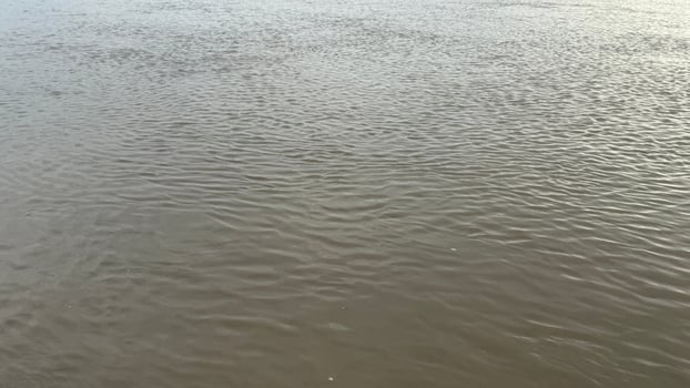The flowing river reflects sky and light, creating an abstract water surface texture photo