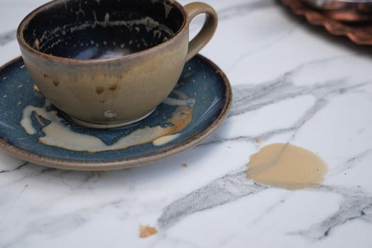 Coffee spills while resting on a marble table surface photo