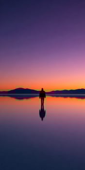 Silhouette of person walking on Salar de Uyuni at sunset photo