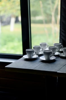 white cups and saucers neatly arranged on a wooden table photo
