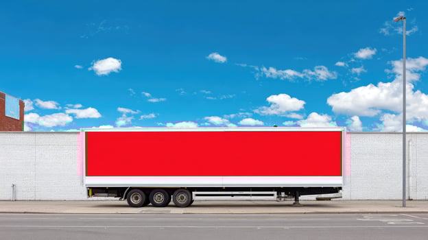 A red trailer truck parked in front of a white building photo