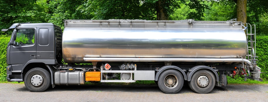 A large silver tanker truck parked in front of a green field photo