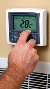 A man is adjusting the temperature on a thermostat photo