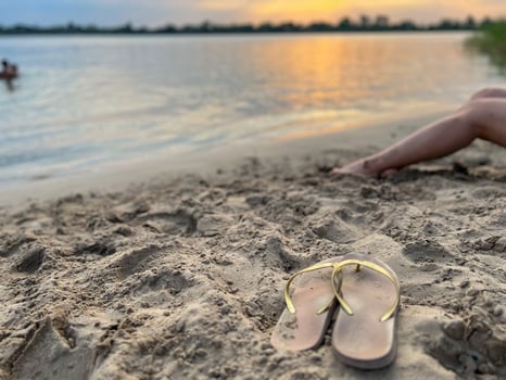 Woman relaxing on the beach with flip flops at sunset photo