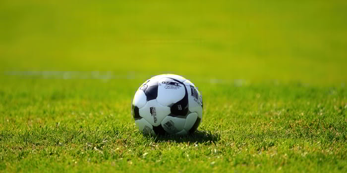 A soccer ball rests on a lush green field, ready for play on a sunny day. photo