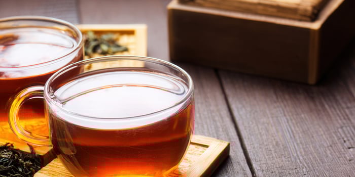 Two glass cups of tea are on a wooden table, creating a cozy and warm scene. photo