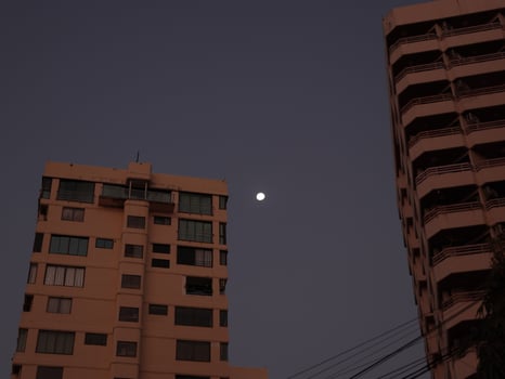 A Beautiful Moon Over an Urban Skyline as the Day Turns to Dusk and Night Approaches photo