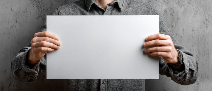 Person holding blank sheet of paper against wall photo