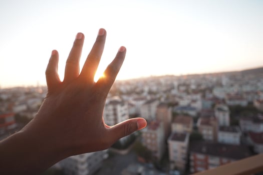 Hand reaching for the sunset over a city skyline photo