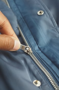 Hand zipping a blue jacket in a casual setting photo