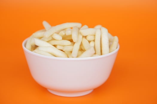 Crispy potato sticks served in a white cup with a vibrant orange background. A fun, crunchy snack perfect for kids and parties. Bright, playful, and flavorful his treat adds color, joy to snack time. photo