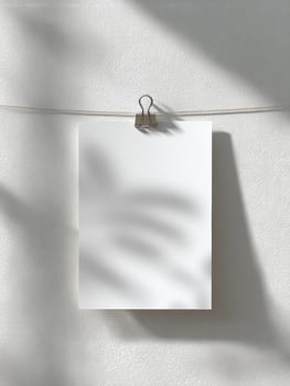Blank white paper hanging on clip with shadow on textured wall background photo