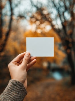 Female hand holding blank card in autumn forest setting photo