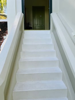 White stairs with smooth surfaces ascend to a doorway with a pale green door. photo