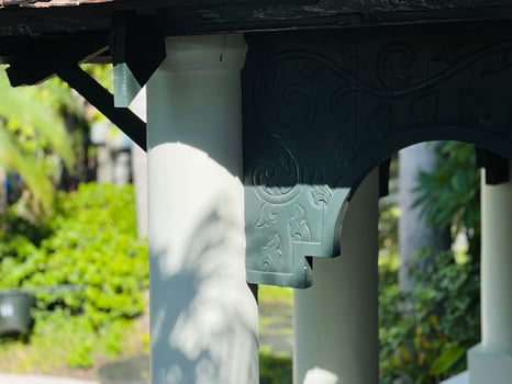 Dark wooden architectural element with ornate floral carvings against a white wall. photo