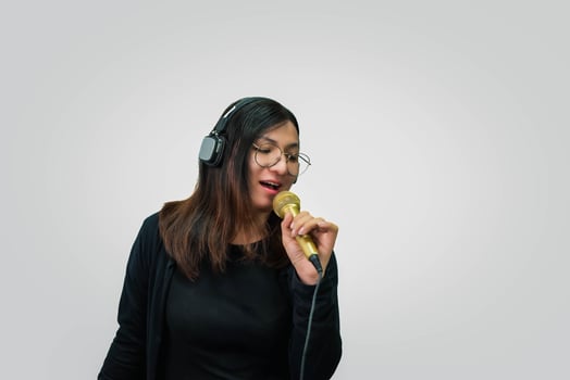 A woman in headphones singing into a microphone photo