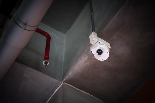 A security camera is mounted on the ceiling of a building photo