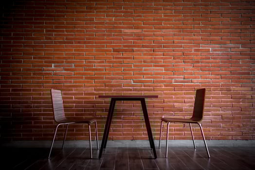 Two chairs and a table in front of a brick wall photo