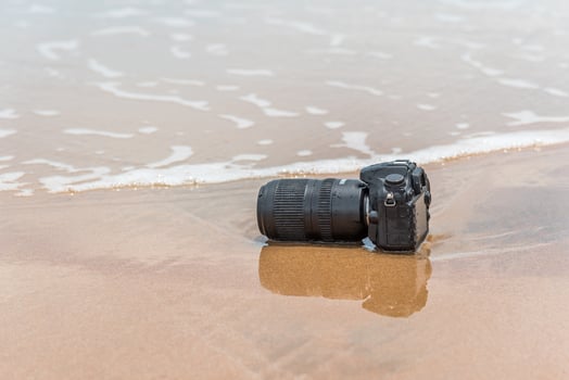 A camera on the beach with waves in the background photo