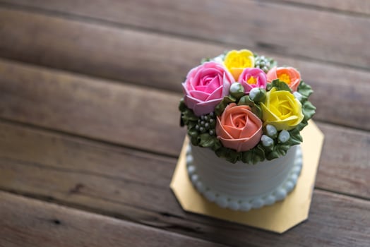 A small cake with colorful roses on top of a wooden table photo