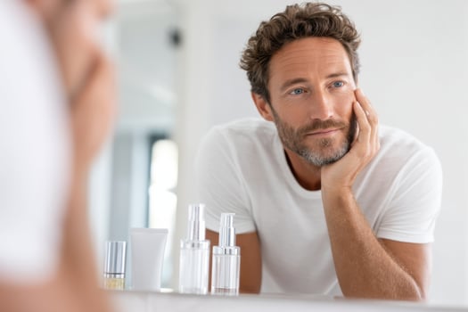 Self-care routine of a younger man applying skincare products in a bright bathroom photo