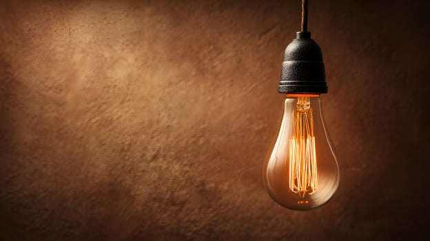 Glowing vintage light bulb hanging against textured wall photo