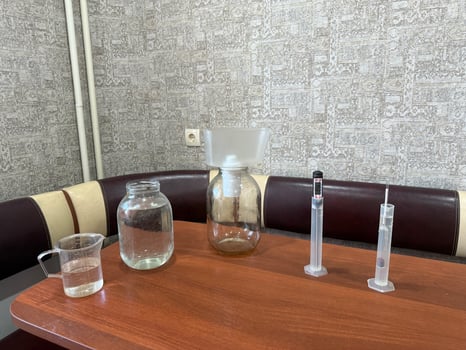 Glass jars, hydrometer, measuring cup, and other tools are arranged on a table, suggesting the preparation of ingredients for crafting homemade alcoholic beverages photo