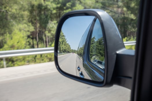 Reflection of a Road and Trees in a Side Mirror While Driving Along a Scenic Route in Bright Daylight photo