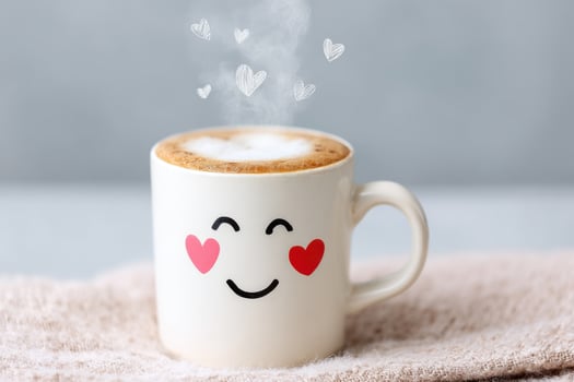 Steaming cup of coffee with hearts rising above it, placed on a soft surface photo