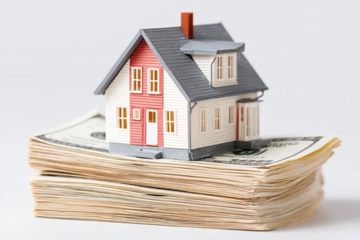 Miniature house model placed on top of large stack of dollar bills photo