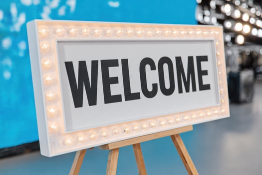 Illuminated welcome sign displayed on wooden easel greeting attendees at a hybrid event photo