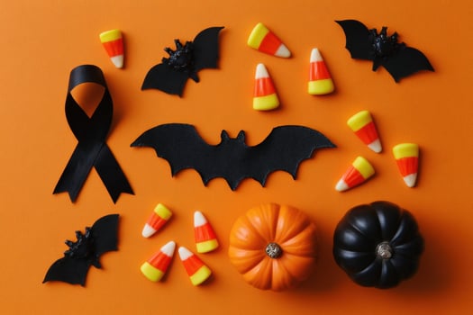 Halloween Flat Lay with Candy Corn, Bats, and Pumpkins on Orange Background photo