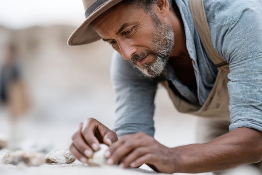 Middle-aged Hispanic male archaeologist examining fossils in a vibrant outdoor setting during a sunny day photo