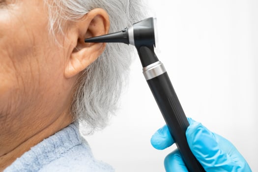 Otolaryngologist or ENT physician doctor examining senior patient ear with otoscope, hearing loss problem. photo
