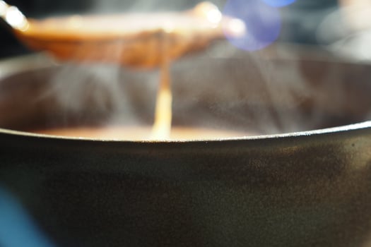 A pot of stew simmers on the stove with steam rising up photo
