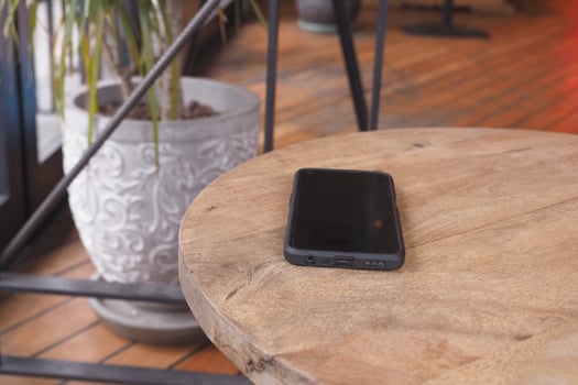 Black smartphone rests on wooden table. lost smart phone concept photo