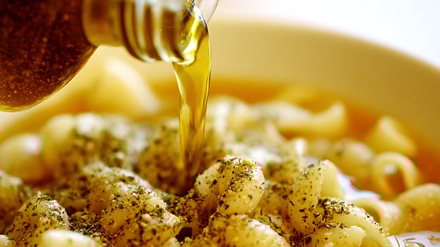 Pouring Golden Olive Oil Over Seasoned Pasta in a Delicious Dish. photo
