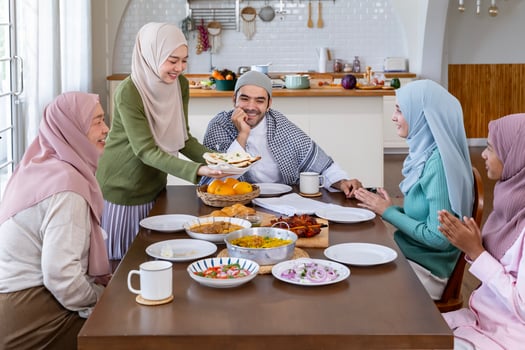 Middle eastern muslim housewife woman in hijab is serving naan bread to family dining table with her husband and relatives during Eid Mubarak, Ramadan festival for feast and gathering photo