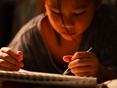 Cute little girl drawing with a pencil at home, close-up of her hand in action as she concentrates on her artwork. photo