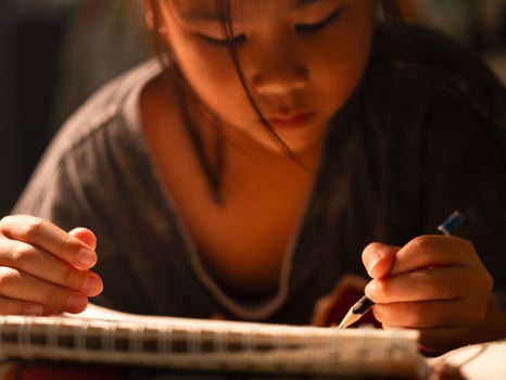 Child hand sketching with a pencil on white paper, highlighting early childhood creativity and home learning environment. photo